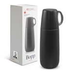 A drink bottle in matte black with a green handle, alongside its packaging featuring a logo.