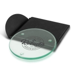 A round, transparent glass coaster in a black presentation packaging, featuring a logo in the centre.