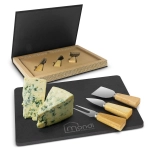 A slate cheese board set featuring a black board, three cheese knives with wooden handles, and blue cheese.