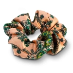 A peach patterned hair scrunchie with green floral designs, featuring a subtle sheen and a soft fabric texture.