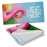 A vibrant beach towel featuring a pink flamingo design against a blue background with tropical elements. It has a logo.