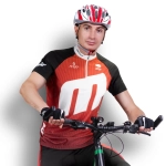 A male cyclist wearing a red and black custom cycling jersey and a helmet, positioned on a bicycle. The jersey features a logo.