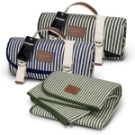A striped picnic blanket in navy blue and green, featuring leather accents and a logo. One blanket is rolled, the other unfolded.