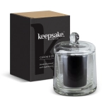A glass candle in a cloche with a black candle inside, paired with a stylish box, featuring a logo.