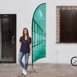 A medium feather flag kit in teal with a logo, displayed beside a person outdoors.