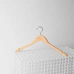 A wooden hanger with a silver hook, featuring a logo, resting on a white wire grid.