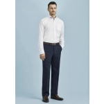 A man stands wearing flat front navy blue slacks paired with a white shirt and brown belt, against a light blue background.