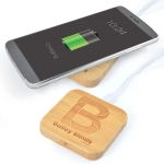 A bamboo wireless charger with a smartphone on top, showing a charging battery icon and featuring a logo.