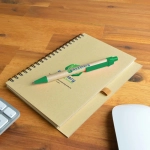 A notebook with a spiral binding and a green Matador pen resting on it, featuring a printed logo.