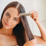 A woman is using a Lynx Wheat Fibre Comb to style her long, straight hair.