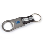 A drink bottle opener in silver metal with a black fabric handle and a ring for keychain attachment.