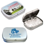 A silver tin filled with white sugar-free breath mints, featuring different printed designs on the exterior.