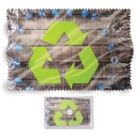 A green recycled symbol lens cloth with a textured design, featuring blue cleaning bottles on a wooden background.