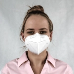 A white N95 respirator face mask worn by a person, featuring a logo and a plain background.