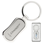 A silver keychain with a sleek design and a circular keyring, presented in a black box. It features a logo.