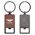 A metal keychain featuring a rectangular design with a wooden centre and a bottle opener at the base, includes a logo.
