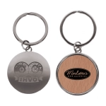 A round keychain in silver with a wood-patterned side featuring a logo and design elements.