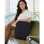 A black backpack with a front pocket, shown on a woman sitting on a green bench in a bright, modern environment.