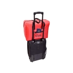 A red emergency travel bag is positioned on top of a black wheeled bag, with a passport visible in the front pocket.