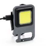 A grey LED multi-tool with a square light panel and a clip for attachment. Features a charging port on the side.