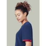 A navy scrub top with a burgundy accent on the sleeve, worn by a woman with curly hair.