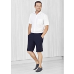 A man wearing navy cargo shorts and a white short-sleeve shirt, standing in a light-coloured setting.