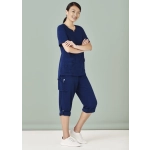 Navy women's scrub top and slim leg scrub pant, featuring pockets and a relaxed fit, set against a light green background.