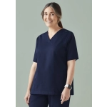 A woman models a navy scrub top featuring a V-neck and side pockets, with a logo on the sleeve.
