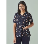 A navy scrub top featuring a playful space print with planets, astronauts, and stars. Includes a pocket and logo.