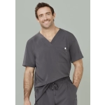 A man wearing a grey V-neck scrub top with a pocket. The scrub top features a loose fit and casual style.