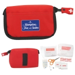 A red first aid kit with a logo, containing scissors, bandages, antiseptic wipes, and various medical supplies.