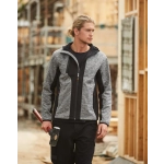 A work jacket in grey and black, featuring a hood and a logo, worn by a model on a construction site.