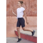 A model wearing black women's Luna bike shorts paired with a white t-shirt and black athletic shoes.