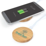 A bamboo wireless charger in a circular shape with a logo, next to a smartphone displaying a charging battery icon.