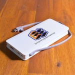 A white power bank with a gray strap and multiple ports, featuring a logo on its surface.
