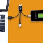 A Kinetic Square Glow Cable in black connects a laptop and a phone, with various charging tips included.