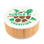 A round speaker made of bamboo with a white top featuring a turtle logo and the text "TURTLE CREATIVES."