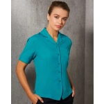 A teal short sleeve overblouse with a button-up front and a pocket, featuring a collar.