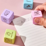 A set of colourful rubber erasers in pastel shades, including purple, pink, and blue, beside a lined notepad.
