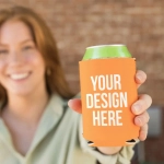 A drink bottle is held by a smiling person, featuring a bright orange neoprene stubby cooler with a design space.