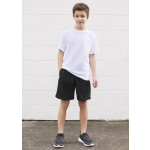 A young boy poses in a white t-shirt paired with black sports shorts, standing against a white wall.