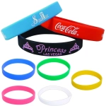 A collection of silicone wristbands in various colours including blue, red, black, green, pink, yellow, and white, featuring logos.