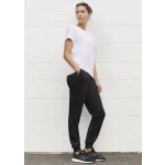 A woman stands in profile wearing a white t-shirt and black track pants with pockets, complemented by black sneakers.