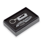 A black gift box containing a silver multi-tool and keyring accessory, presented on a plush interior.