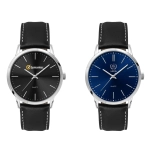 A men's dress watch with a black dial and silver hands, featuring a leather strap. Another watch has a blue dial.