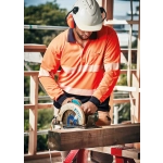 A worker in a high-visibility orange long-sleeve polo with reflective tape operates a circular saw on a construction site.