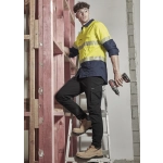 Mens lightweight outdoor pant in black, paired with safety boots, on a ladder in a construction setting. Features a logo.
