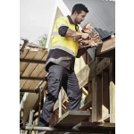 A man in high-visibility clothing uses a nail gun while wearing navy lightweight drill cargo pants on a construction site.