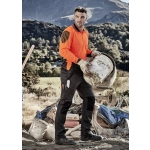 A worker in an orange high-visibility shirt and black tough pants, holding a bucket on a job site with mountains in the background.