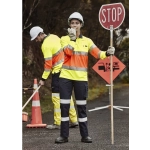 A woman in high-visibility workwear holds a stop sign, while a man in similar gear works nearby. Both wear hard hats.